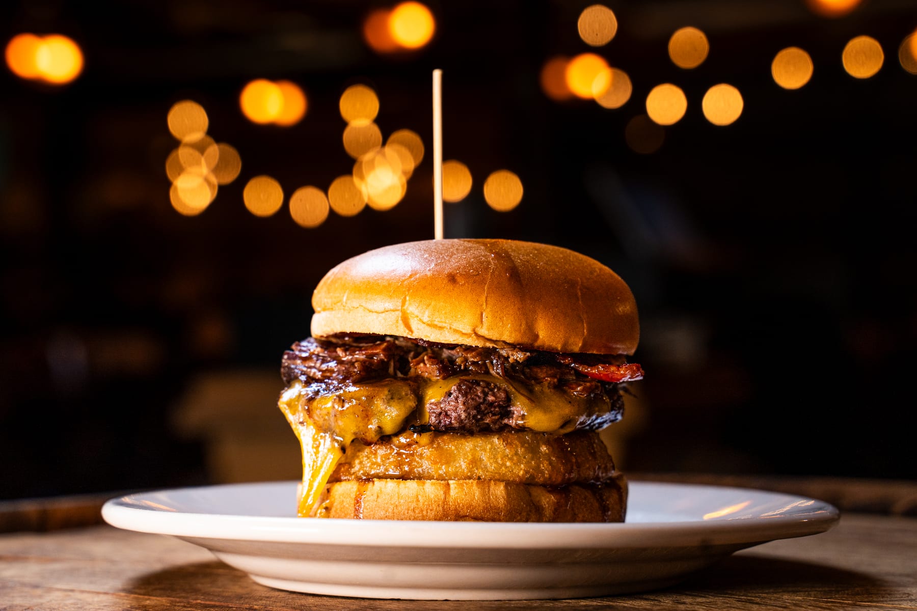 Signature BBQ Burger at Hop N Grape in Longview, WA — burger patty topped with brisket, pulled pork, bacon and a crispy onion ring on a brioche bun